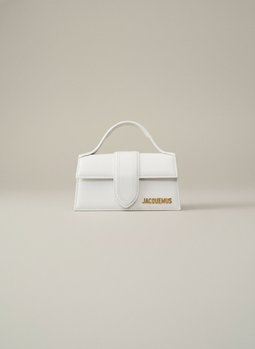 Person holding a white handbag with 'Jacquemus' branding against a neutral background